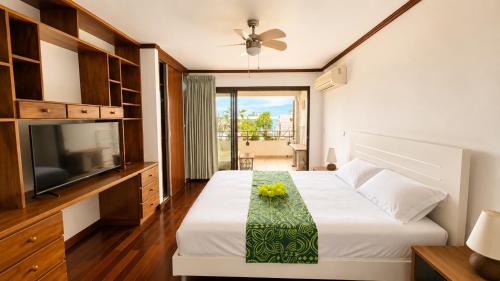 a bedroom with a bed and a flat screen tv at Blue Lagoon - Studio avec accès piscine in Papeete