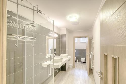 La salle de bains est pourvue de 2 lavabos et d'une paroi en verre. dans l'établissement Apartment Promenáda 35, à Karlovy Vary