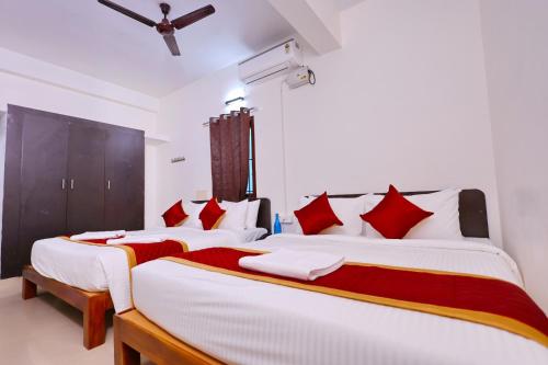 two beds in a room with red and white pillows at Hotel Shree Laksha Residency Madurai in Madurai