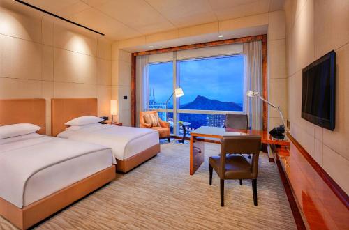 a hotel room with two beds and a desk and a window at Grand Hyatt Shenzhen in Shenzhen