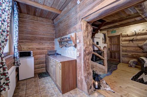 a kitchen in a log cabin with wooden walls at Góralski Domek z kominkiem - Highlander Wooden House in Murzasichle