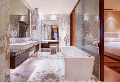 a bathroom with a tub and two sinks and a bed at Grand Hyatt Shenzhen in Shenzhen