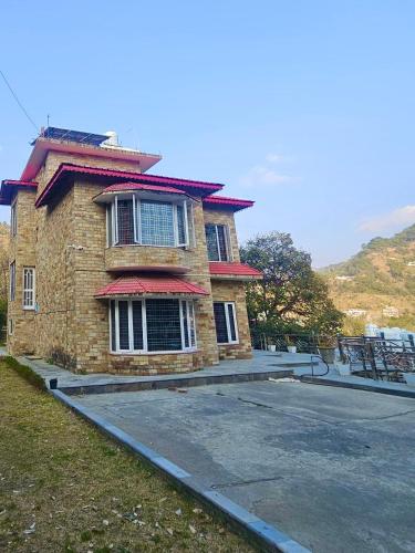 a brick house with a red roof on a street at Voyager stone cottage in Bhīm Tāl
