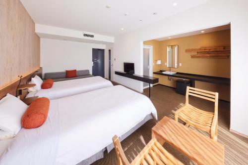 a hotel room with two beds and a desk at Hotel Rotterdam Huis Ten Bosch in Sasebo