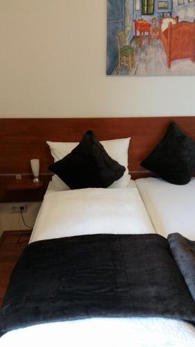 a bedroom with two white beds with black pillows at Ellenbergs Restaurant & Hotel in Heßheim