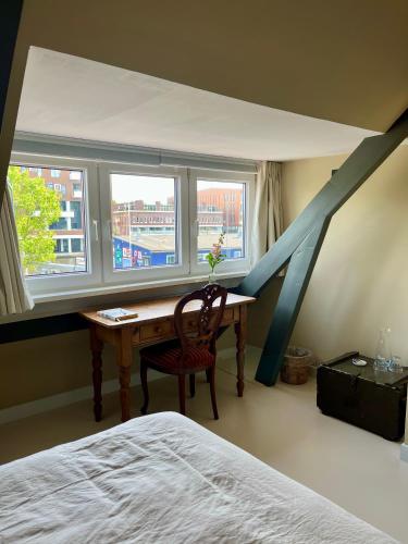 a bedroom with a desk and a bed and a window at Private attic room with workspace & water view in Haarlem