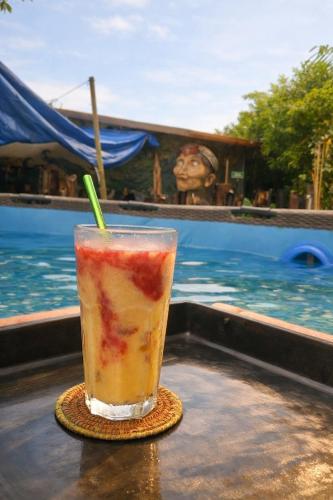 Ein Getränk steht auf einem Tisch neben einem Pool. in der Unterkunft Nomada Hostel in Leticia