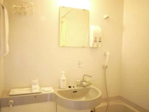 a white bathroom with a sink and a mirror at Shizuoka Town Hotel in Shizuoka