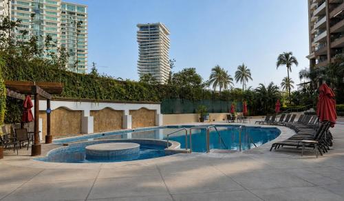 a large swimming pool with chairs and a building at Grand Venetian Comfort in Puerto Vallarta