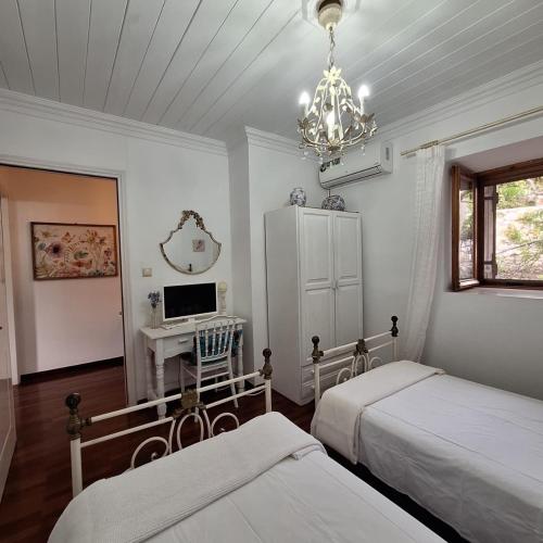 a bedroom with two beds and a desk and a chandelier at Casa di Sofiana by wood and stone in Áyios Pétros