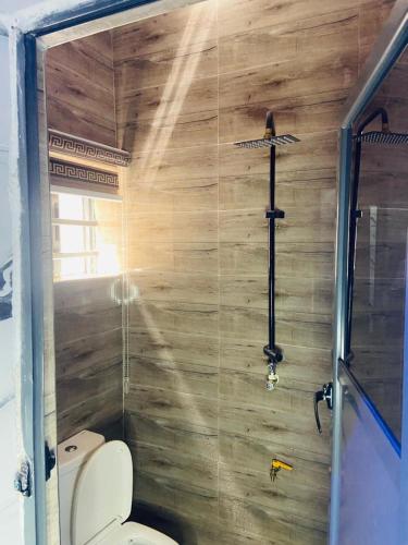 ein Badezimmer mit Toilette und einer Holzwand in der Unterkunft Double Homes in Agege