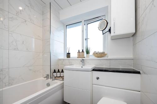 a white bathroom with a sink and a bath tub at Peaceful hideaway with homely comforts in Timperley