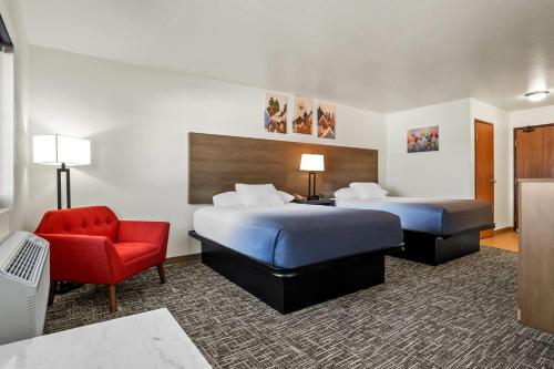 a hotel room with two beds and a red chair at Super 8 by Wyndham Montpelier - Bear Lake in Montpelier