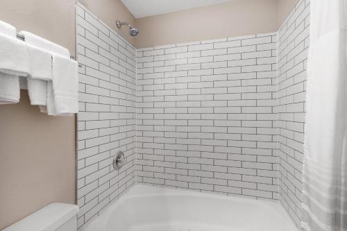 a bathroom with a white tiled shower with a tub at Super 8 by Wyndham Biloxi at the Beach in Biloxi