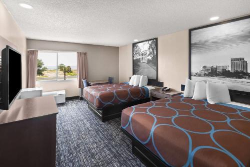 a hotel room with two beds and a flat screen tv at Super 8 by Wyndham Biloxi at the Beach in Biloxi