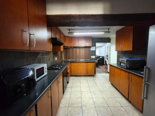 a large kitchen with wooden cabinets and a microwave at Forest Lodge - Richards Bay in Richards Bay