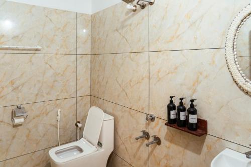 a bathroom with a toilet and three bottles of wine at Kuma Surf House in Kappil