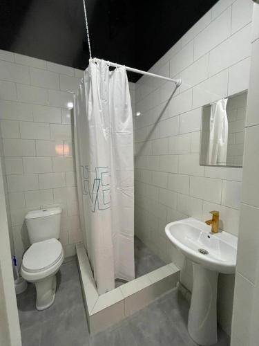 a white bathroom with a toilet and a sink at База отдыха Golden rest in Borovoye