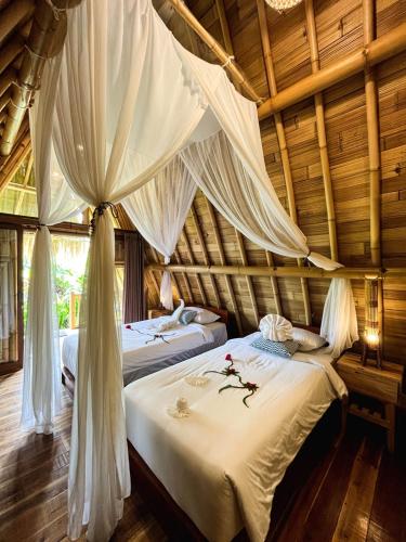 a bedroom with two beds with mosquito netting at Bali Hidden Lemukih in Sawan