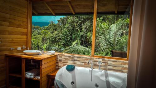 a bathroom with a tub and a large window at LA RUSTICA MiNDO in Mindo