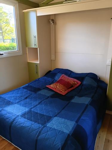 a bedroom with a blue bed with a red pillow on it at Bungalow tonga in Moncetz-lʼAbbaye