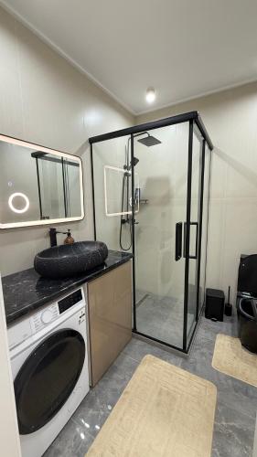 a washing machine in a bathroom with a shower at Yassi Apartment in Türkistan