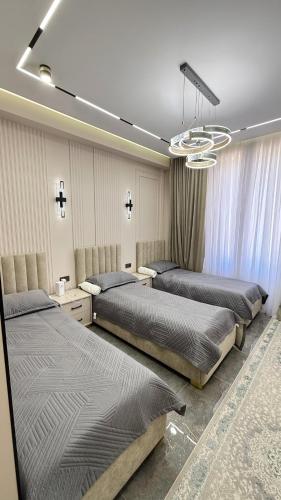 a bedroom with three beds and a chandelier at Yassi Apartment in Türkistan