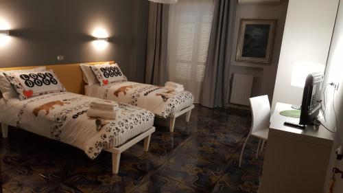 Cette chambre comprend deux lits, un bureau et une télévision. dans l'établissement B&B Villa Elvira, à San Vito