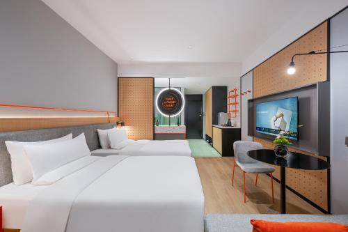 a hotel room with a large bed and a tv at Novotel Living Hangzhou International Convention Center in Hangzhou