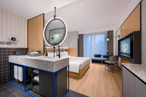 a hotel room with a bed and a mirror at Novotel Living Hangzhou International Convention Center in Hangzhou
