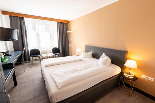 ein Hotelzimmer mit einem großen Bett und einem Schreibtisch in der Unterkunft Skycity Hotel Atrigon in Klagenfurt am Wörthersee