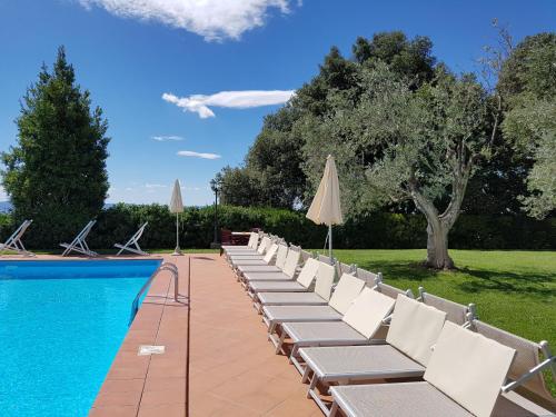 a row of chairs and umbrellas next to a pool at Villa Nencini in Volterra