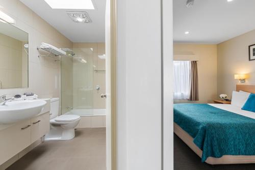 a bathroom with a bed and a sink and a toilet at Bay View Villas in Hobart