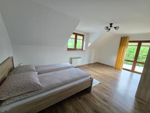 a bedroom with a bed and wooden floors and windows at BIESCZADNIK in Polańczyk