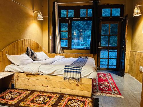 a bedroom with a wooden bed with a large window at Pond & Stone Homestay in Banjār