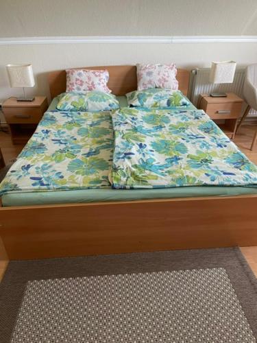 a bed with blue and green sheets and pillows at Kamilla Apartman in Fonyód