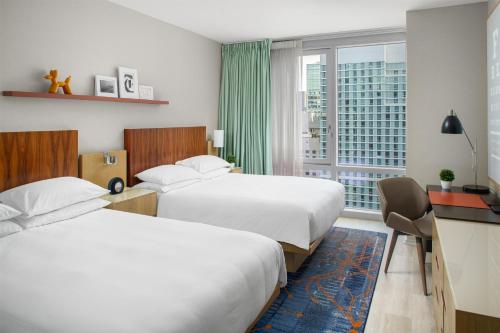 two beds in a hotel room with a window at Hyatt Centric Times Square New York in New York