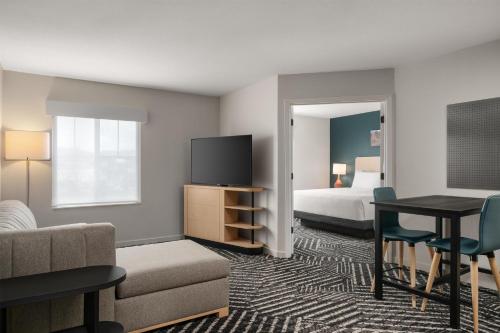 a hotel room with a bed and a desk with a television at Hyatt House Fishkill-Poughkeepsie in Fishkill