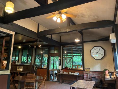 a room with a clock on the wall and tables at Flower Garden in Takamori
