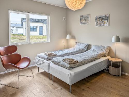 a bedroom with a bed and a chair and a window at Deluxe Family Apartment in Egilsstaðir in Egilsstaðir