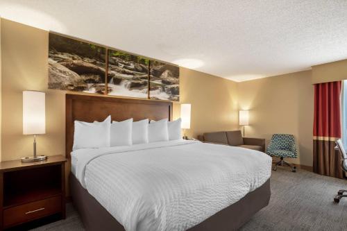 a hotel room with a bed and a chair at Clarion Pointe Cherokee in Cherokee