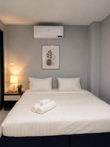 a bedroom with a white bed with two towels on it at Chaba CBP Chiang Mai in Chiang Mai