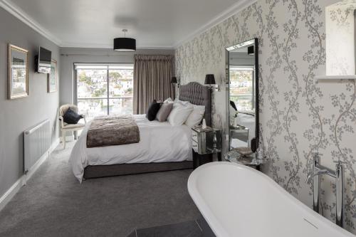 a bedroom with a large bed and a mirror at Driftwood B&B in Brixham