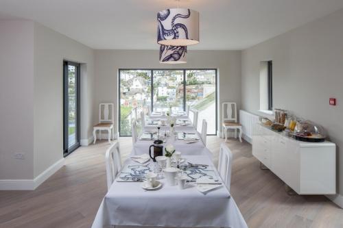 a dining room with a white table with white chairs at Driftwood B&B in Brixham