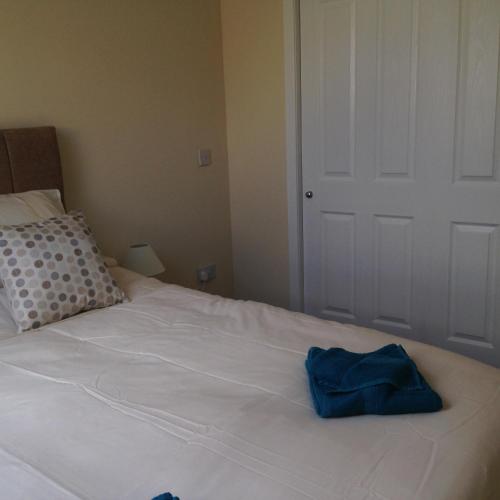 a white bed with a blue bag on it at The Old Coach House in Eyemouth