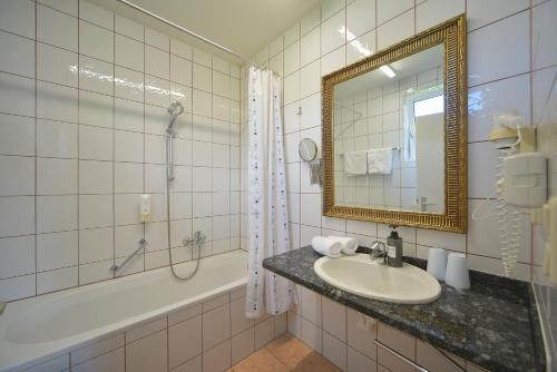a bathroom with a sink and a tub and a mirror at Hotel Klein - Seebodenerhof in Seeboden