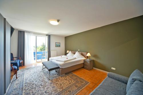 a bedroom with a bed and a couch and a window at Hotel Klein - Seebodenerhof in Seeboden