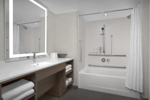 a bathroom with a tub and a sink and a shower at Home2 Suites by Hilton Chelmsford Lowell in Chelmsford