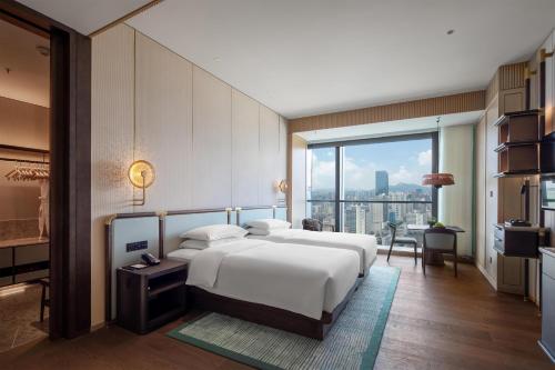 a bedroom with a large white bed and a large window at Grand Hyatt Kunming in Kunming