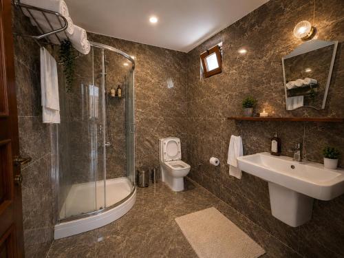 ein Badezimmer mit Dusche, Toilette und Waschbecken in der Unterkunft Lithos Assos in Ayvacık